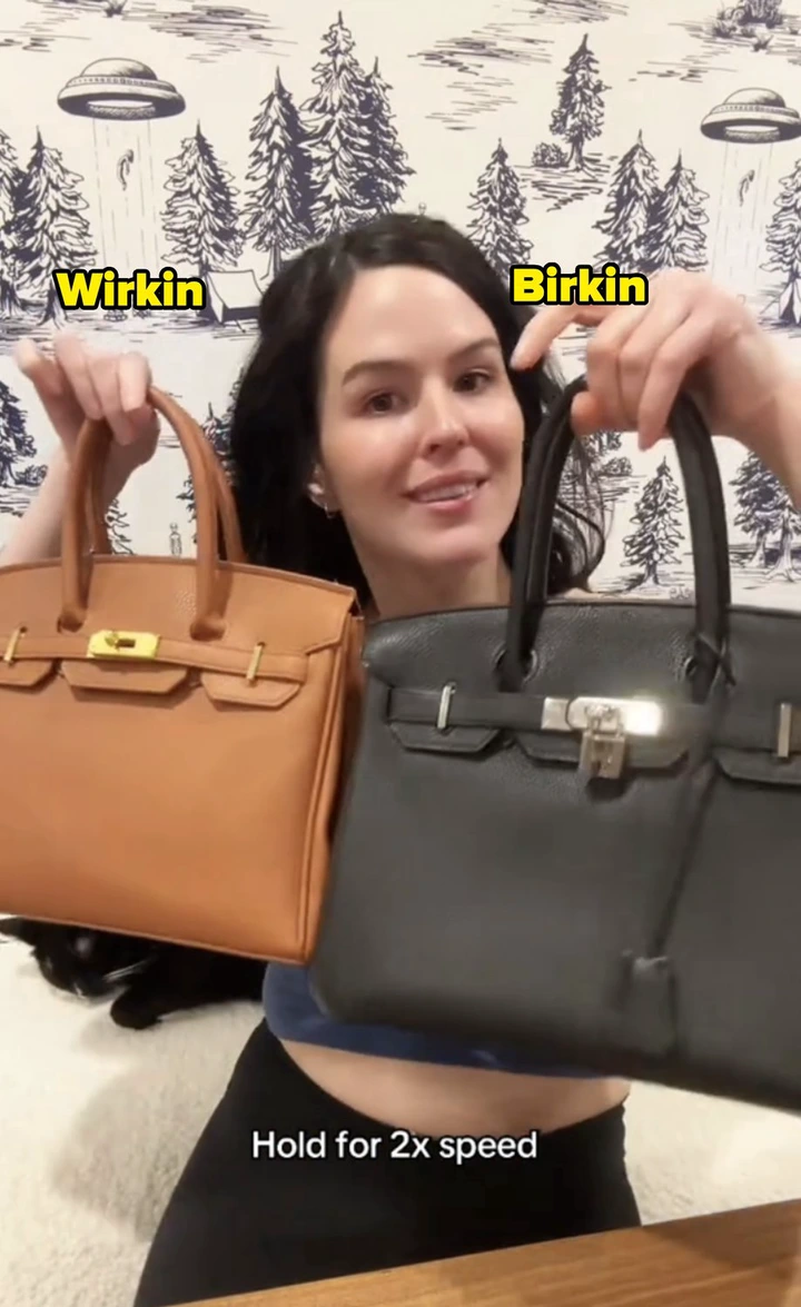 Person holding a tan and black handbag, smiling, with scenic wallpaper in the background