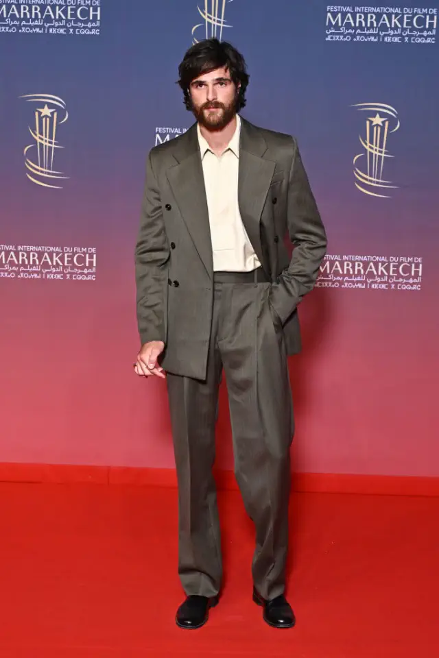 Jacob in a tailored suit poses on a red carpet at a film festival event