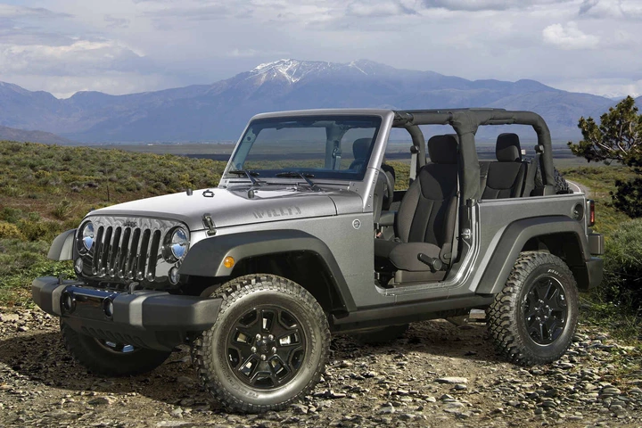A silver 2018 Jeep Wrangler parked outside with its rag top off in left front angle view