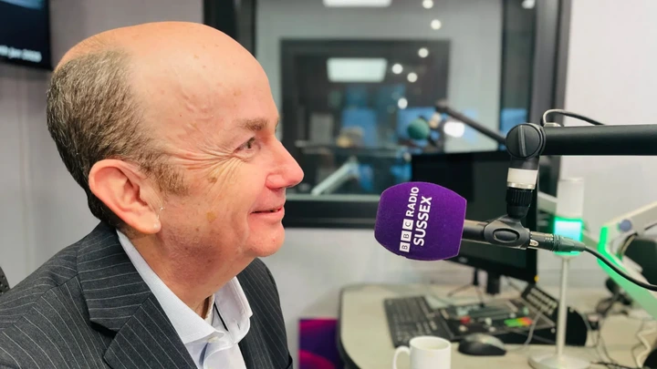 Mark Norman is associated with the BBC. The chief executive of the South East Coast Ambulance Service speaking into a BBC Radio Sussex microphone