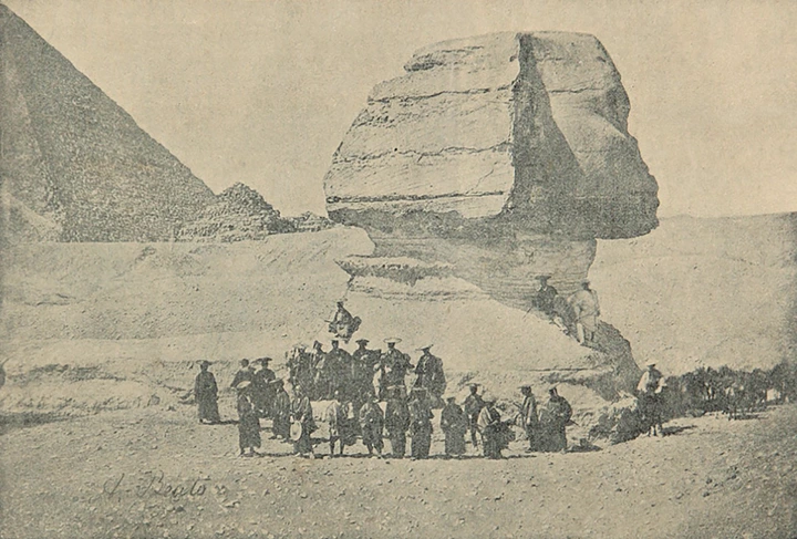 Group of people in front of the Great Sphinx of Giza, with part of a pyramid visible in the background. Early 20th-century photo
