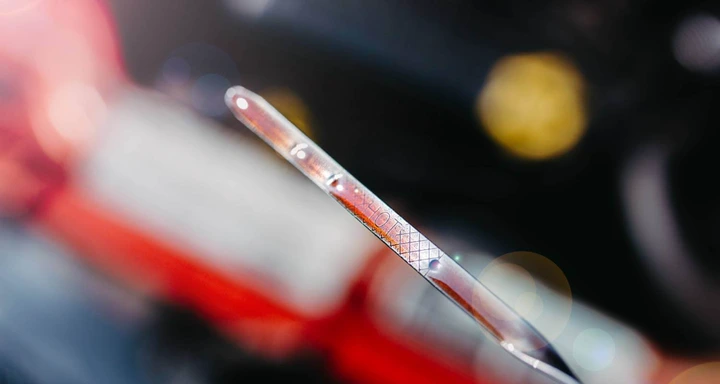 Close-up of a car's transmission dipstick with the word "HOT" on it. The transmission fluid appears to be red.