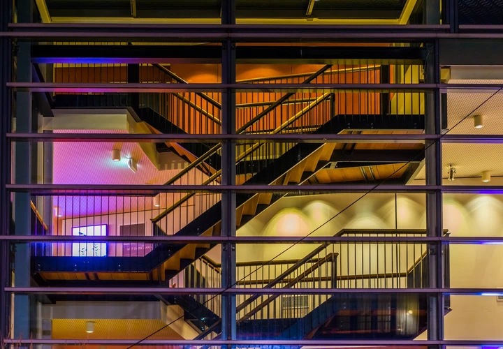 Modern staircase inside a building with multiple levels, visible through large glass windows