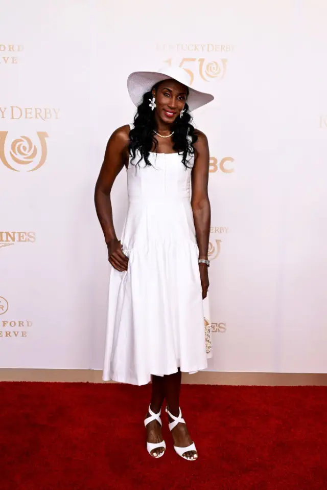 Lisa in a stylish dress and hat on a red carpet at a celebrity event