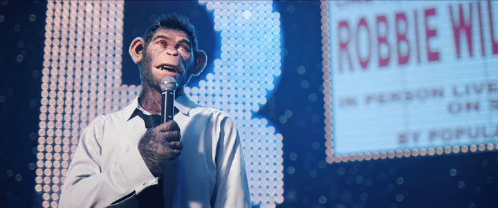 A chimpanzee wearing a white shirt holds a microphone on stage with a sign in the background