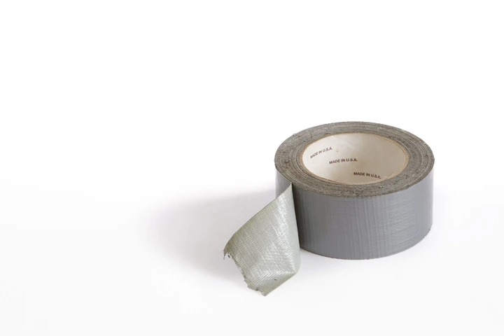 Roll of duct tape with a loose end, placed on a white surface