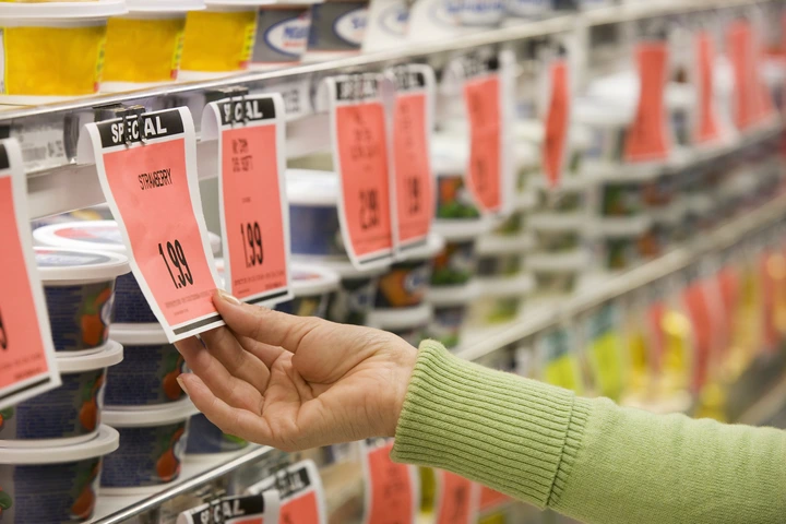 Hand reaching for a yogurt with a sale tag in a grocery store