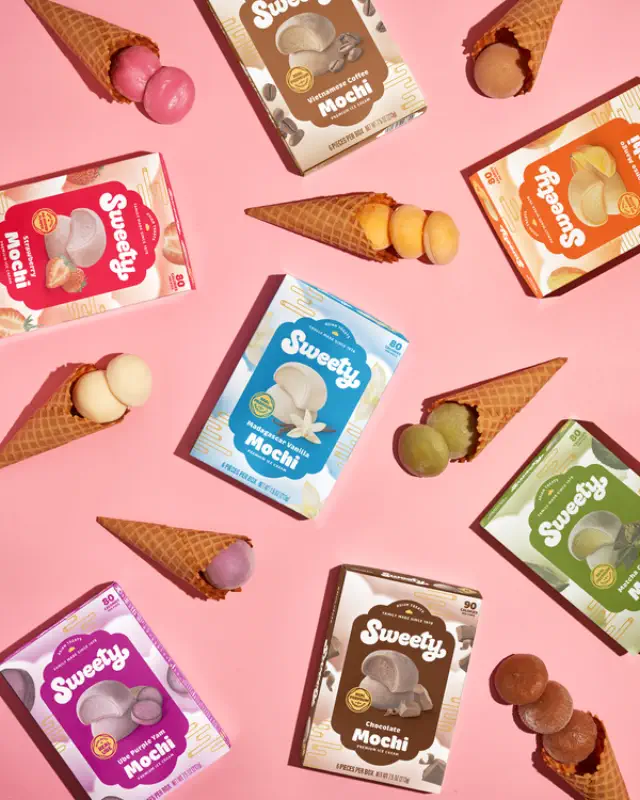 Boxes of Sweety Mochi ice cream in various flavors, surrounded by mochi balls in waffle cones