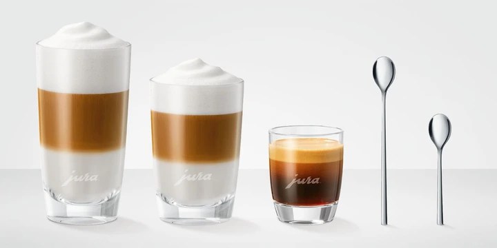Three layered coffee drinks and two spoons are arranged in a row against a plain background, epitomizing the elegance of the ultimate coffee station. Perfectly curated for JURA accessories enthusiasts, each element complements your perfect brew.