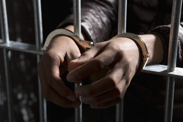handcuffed hands in a jail cell