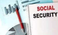 SOCIAL SECURITY written on a notebook placed against a backdrop of a chart.