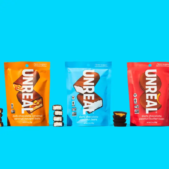 Three bags of Unreal chocolate snacks: peanut nougat, coconut bars, and peanut butter cups, shown with their contents in front