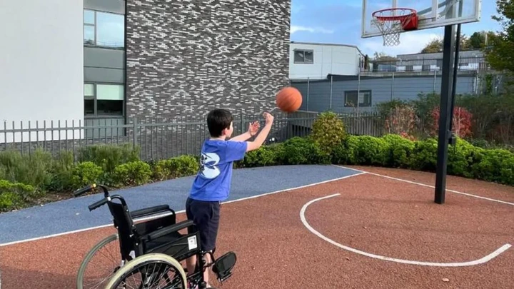 Family pamphlet/PA Real Life Harry is seen in a basketball court standing up from his wheelchair in an attempt to shoot the ball through the hoop.