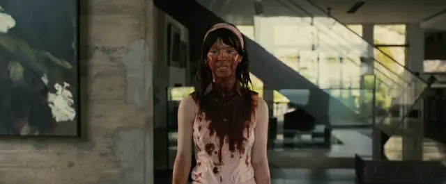 Person in modern home, with chocolate or mud on their face and clothing, standing still and looking forward