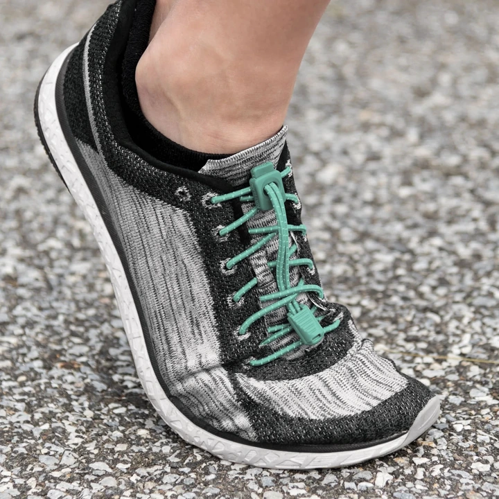 Close-up of a person&#x27;s foot wearing a stylish athletic shoe with uniquely designed laces, suitable for running or casual wear