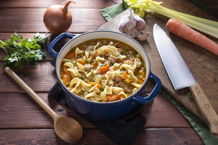 pot of chicken noodle soup with fresh vegetables and ingredients