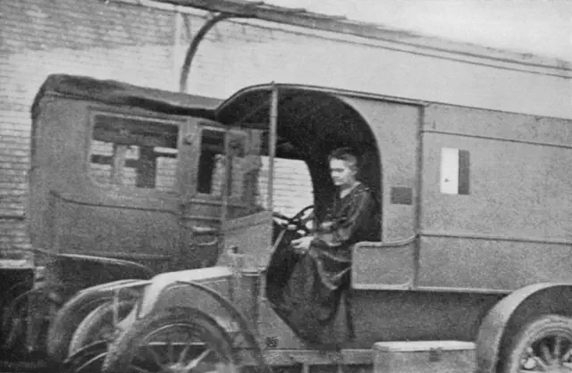 Historical photo of a person seated inside an early 20th century vehicle, possibly a medical transport