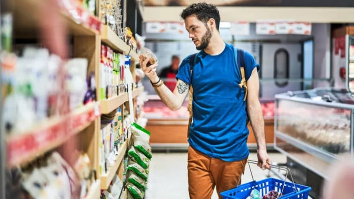Man looking at packed food in supermarket (stock photo)