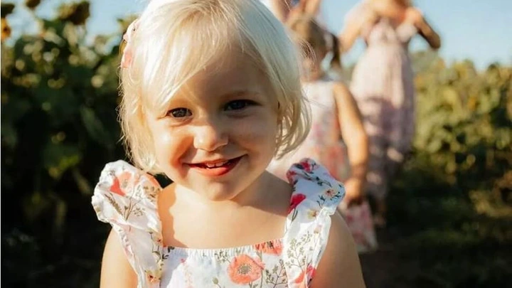 Ava Hodgkinson wears a dress and smiles in a field