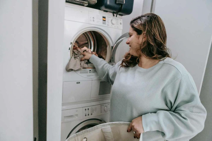A woman happily folding laundry (Image Source: Pexels | Sarah Chai)