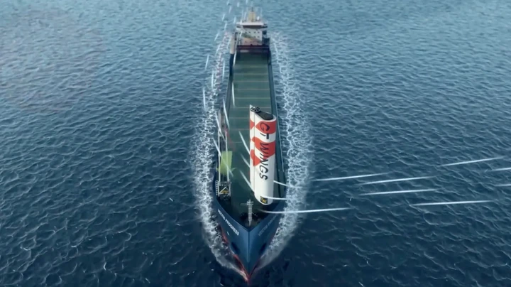 GT Wing A computer-generated image of a cargo ship sailing through the sea. Towards the bow is a tall sail-like structure which is white and red. White streaks have been drawn to show how the wind flows over the sail