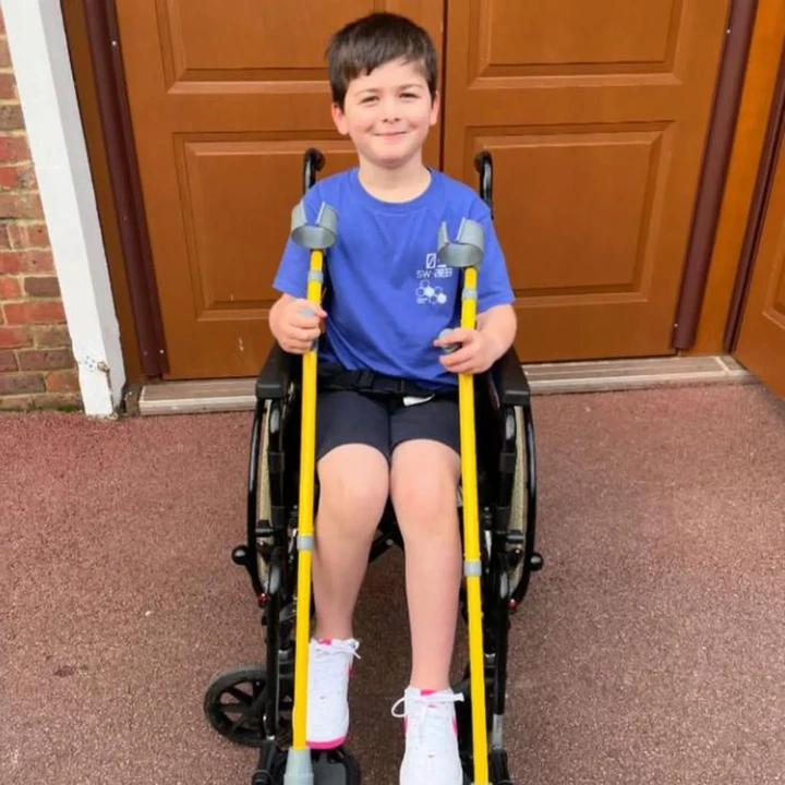 Family pamphlet/PA Real Life Harry is seen in a wheelchair smiling while holding a pair of yellow crutches. 
