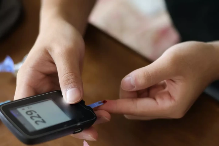 An Asian teenager with type 1 diabetes uses an at home glucometer to test his blood sugar levels.