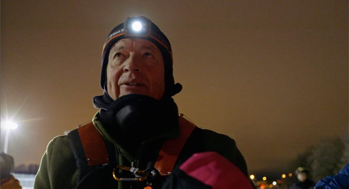 a person wearing a harness and a headlamp in a nighttime setting