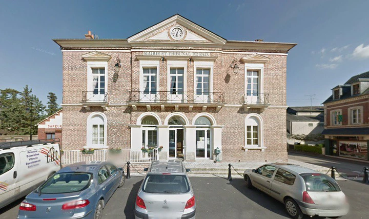 Exterior view of the town hall in the small French town of Thiberville with parked cars in front
