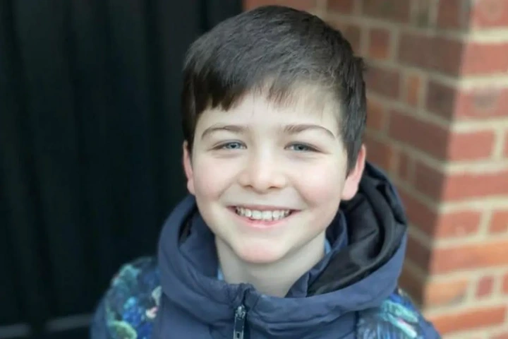 Family pamphlet/PA Real Life Harry Goulden is seen from the neck up, smiling at the camera. He is wearing a coat with a schoolbag over his shoulders.
