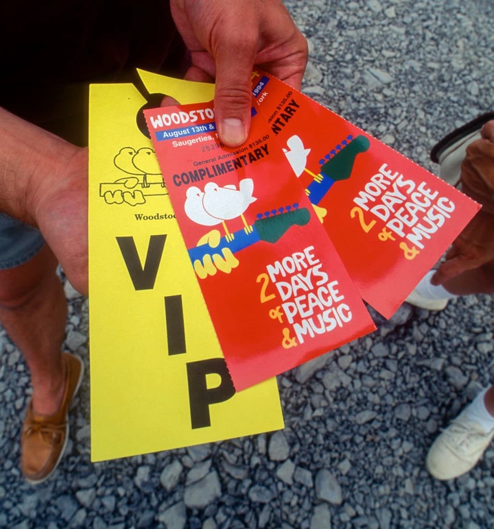 Person holding Woodstock 1994 VIP passes and complimentary tickets, promoting two more days of peace and music
