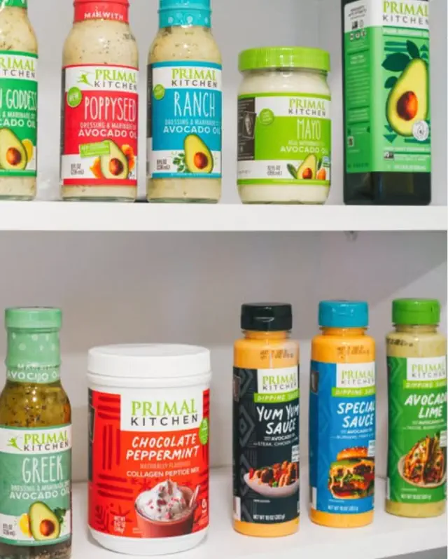A variety of Primal Kitchen sauces, dressings, and mixes neatly arranged on a pantry shelf, highlighting options like ranch, poppyseed, and avocado mayo