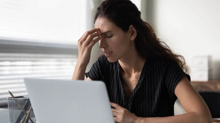 Woman looking stressed holding her head in her hands.