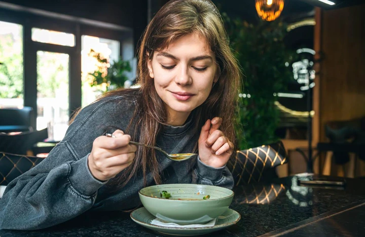 Attractive woman eating vegetable soup in a cafe, healthy eating, veganism and vegetarianism, copy space.