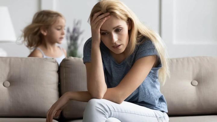 Woman looking tired and stressed while her kids runs around her.