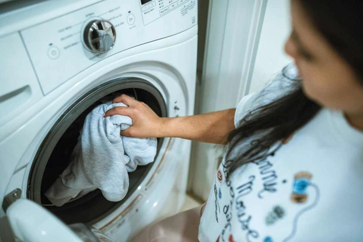 A woman loading laundry into the washing machine (Image Source: Pexels | RDNE Stock project)