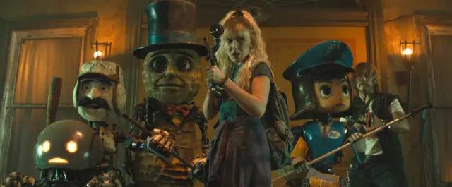 A woman stands confidently with four large, animated doll-like characters, each dressed uniquely with hats and props, as if preparing for an adventure
