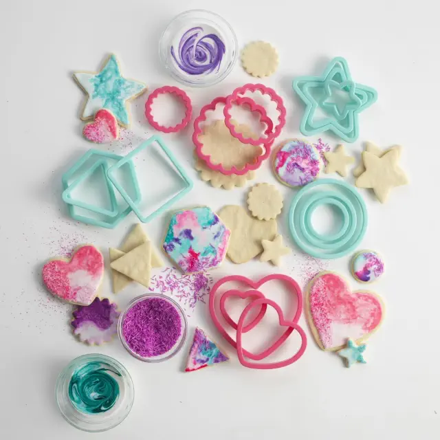 Assorted cookie cutters and decorated cookies with colorful icing and sprinkles, suitable for baking enthusiasts