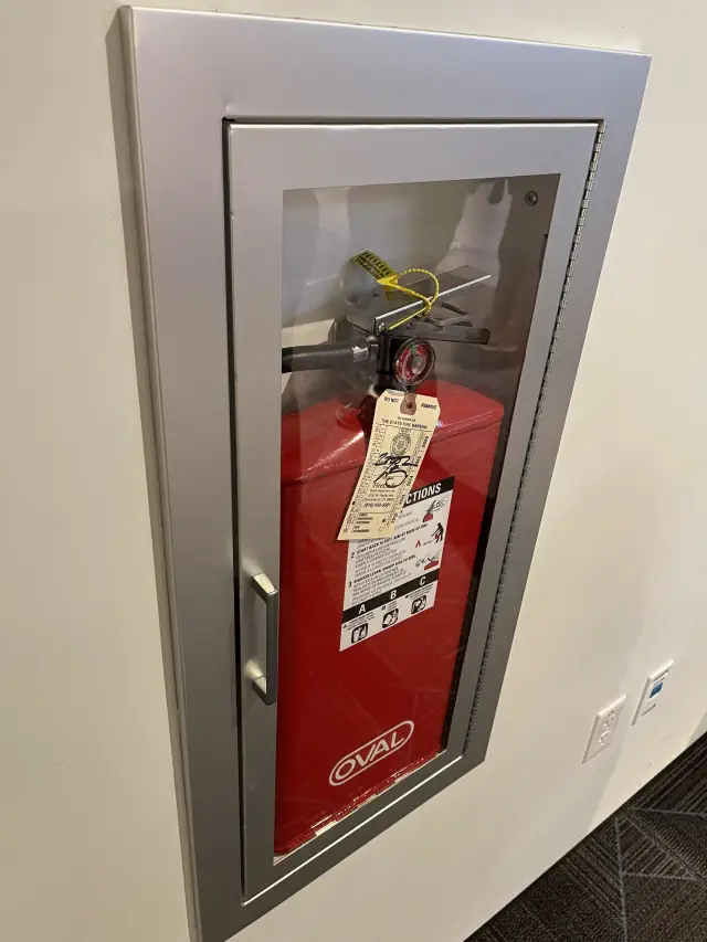 Fire extinguisher in a wall cabinet with inspection tags attached