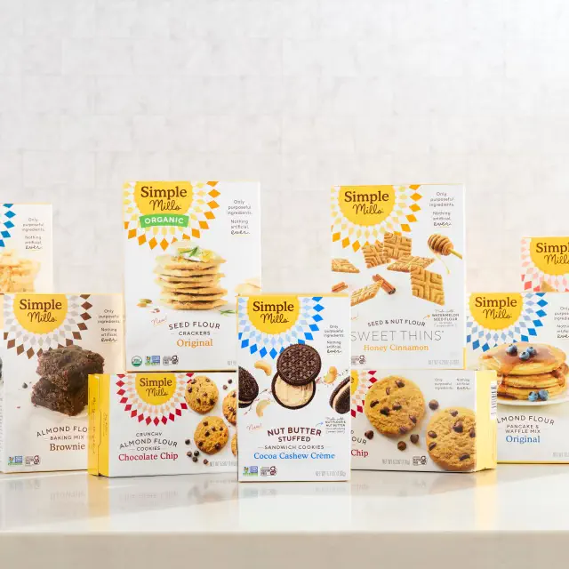 A selection of Simple Mills packaged snacks, including cookies and crackers, displayed on a kitchen countertop